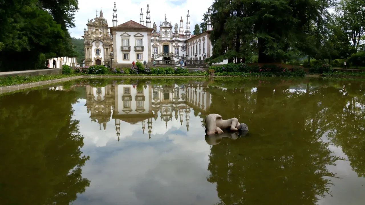 a statue in a body of water with a building in the background